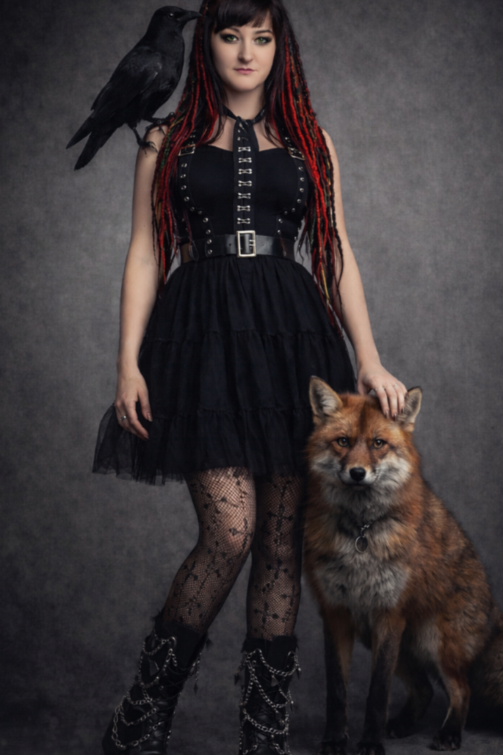 Woman in a black outfit with a fox and a crow on a dark background